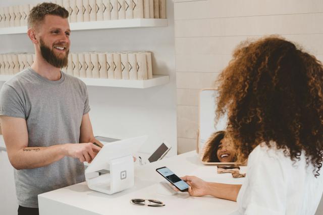 A shop owner serving a customer at a retail counter