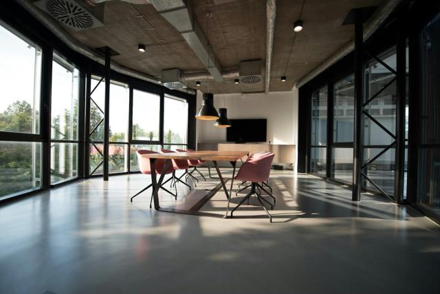 A quiet open-plan office with a meeting table set against full-height windows